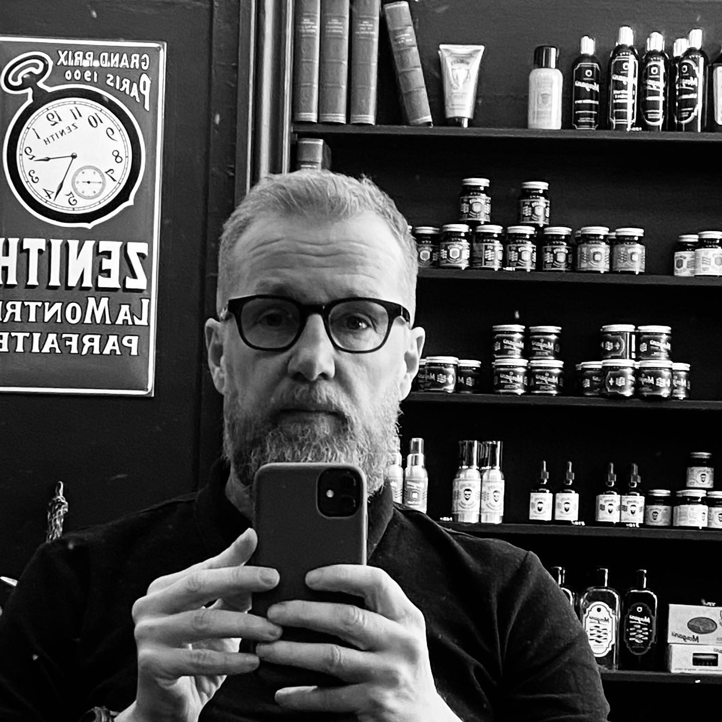 Torben Larsen foran hylderne med barberprodukter i butikken, sort/hvid portræt
